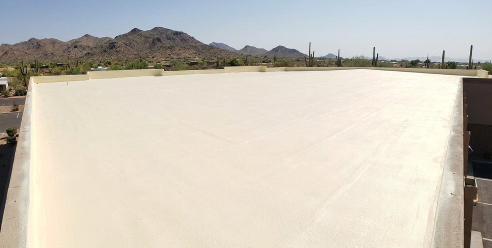 Seamless white spray foam roof on a commercial building in Mesa, Arizona, with desert mountains in the background